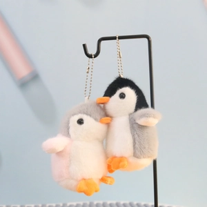 Close-up of cute plush penguin keychains with metal bead chains in grey and pink colors