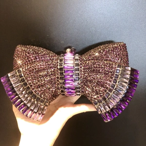 Detailed close-up of a purple rhinestone bow clutch purse for luxury evening banquets
