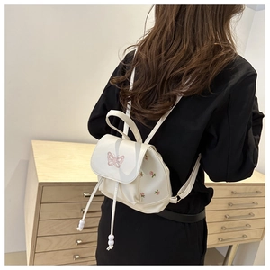 White leather backpack featuring pink butterfly embroidery and floral detail on model