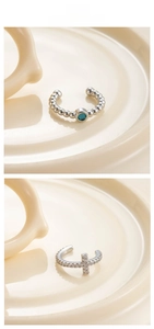 Détail de bagues d'oreille serpent argentées et boucles croix sur plateau blanc