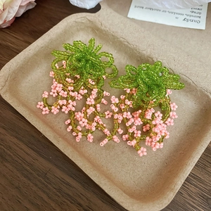Detail of handmade flower bead tassel earrings with pink blossoms and green leaves