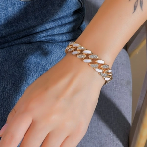 Dettaglio del bracciale a maglia cubana dorata con smalto bianco e cristalli incastonati