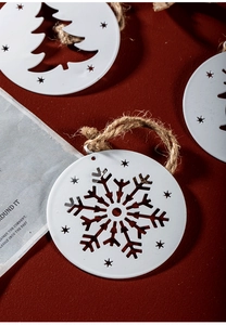White metal Christmas ornaments with snowflake and tree cutouts on red background