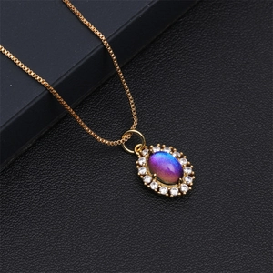 Macro-opname van gouden ketting met ovale hanger, blauw-paarse steen en micro-zirkonen