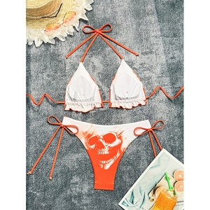Women's two-piece white bikini set with orange skull print and ruffle halter top