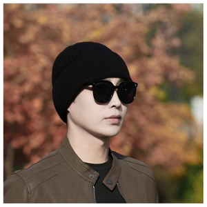 Close-up of a black ribbed knit beanie worn by a model in an outdoor autumn setting