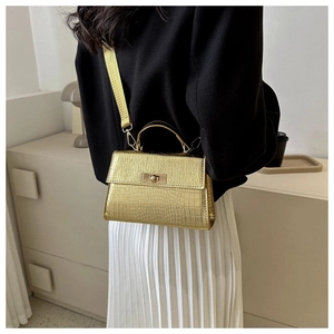 Detail of golden crocodile pattern handbag with metal lock and adjustable strap
