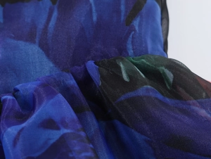Détail de la texture en organza bleu marine à imprimé floral et volants plissés