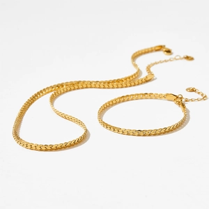 Gold flat Cuban chain necklace and bracelet set with lobster clasp on white background