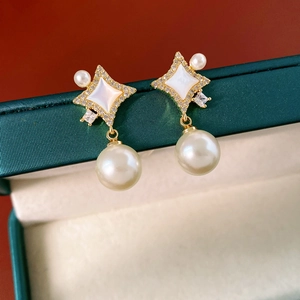 Gros plan détaillé de boucles d'oreilles étoile avec perles et base dorée sertie de zircons