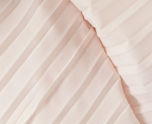 Detailed close-up of light pink pleated chiffon fabric texture and edge stitching
