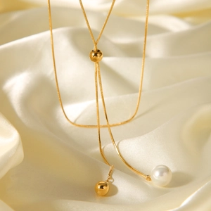Macro detail of golden snake chain with adjustable pearl and ball drop on silk