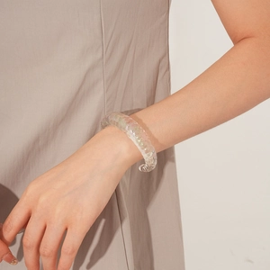 Detailed view of translucent chunky iris bangle with twisted texture on model's wrist
