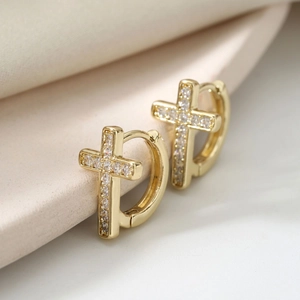 Elegant gold cross hoop earrings featuring sparkling zircon inlay on soft silk background
