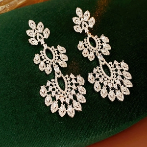 Détail des boucles d'oreilles vintage fleurs et glands en zircon sur velours vert