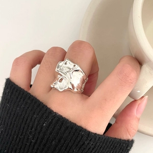 Detailed view of large irregular liquid silver ring with melted texture on polished surface