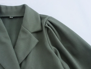 Detailed close-up of green wool coat showing blazer collar and puff sleeve texture