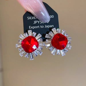 Macro shot of silver zircon red crystal sunflower earrings on a black display card