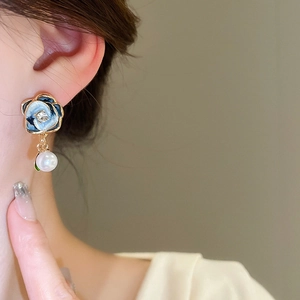 Close-up of blue gradient flower earrings with pearl drop on model wearing look