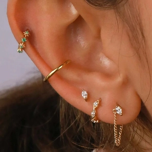 Close-up of gold layered earrings with marquise zircon studs and linked chain charms