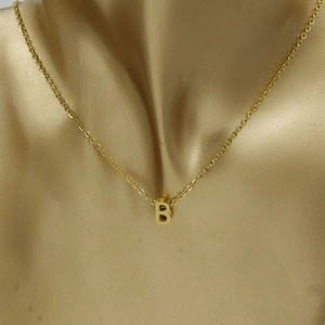 Detailed view of a 3D letter B pendant on a polished gold stainless steel chain