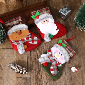 Christmas plush gift stockings featuring Santa, snowman, and reindeer on a wooden background