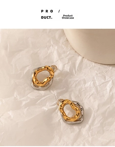 Detailed close-up of two-tone irregular wavy earrings on a soft white background