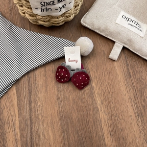 Close-up of strawberry felt hair ties with white pom poms on a wooden table