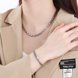 Close-up of stainless steel grid chain necklace and bracelet set on a model