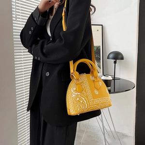 Detail of yellow shell bag with paisley print and matching shoulder strap on black blazer