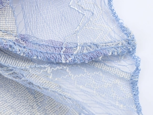 Gros plan sur la dentelle de tulle bleu clair montrant la maille et la finition de l'ourlet