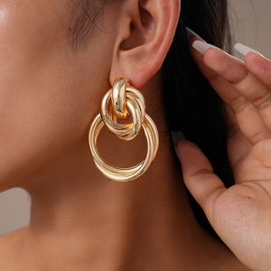 Close-up of golden geometric twisted knot double hoop earrings on model for detail