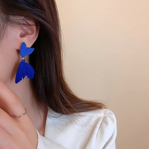 Macro detail of Klein Blue drop earrings with textured fan-shaped wings on model