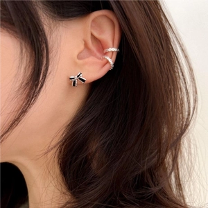 Close-up of elegant black bow earring and silver crystal ear cuffs on model's ear