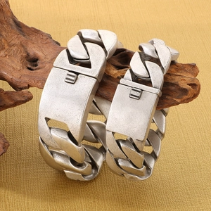 Retro silver steel Cuban chain bracelets in two sizes on natural wood texture background