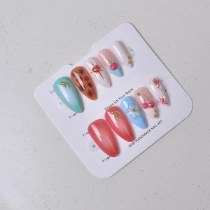 Detail showing 3D cherry patterns and floral press-on nails on a white display card