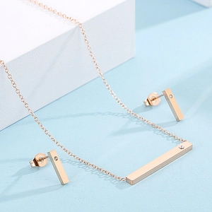 Detail of rose gold bar jewelry set with a single crystal on necklace and earrings