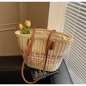 Detail of woven straw tote bag with purple accents and long brown PU leather straps