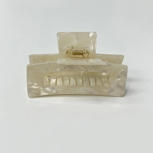Detail of a creamy beige marble pattern hair claw clip with a secure gold metal spring