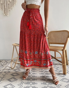 Détail d'une jupe longue rouge à fleurs avec taille élastique et cordon à pompons