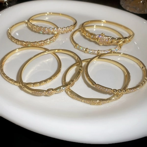 Close-up of gold plated bangles with cubic zirconia stones displayed on white ceramic plate