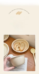 Detail of cream ceramic dinnerware set including round plate, bowl and long handle spoon