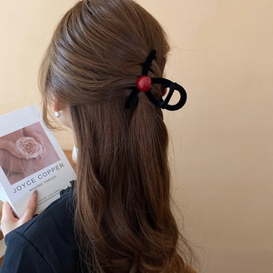 Minimalist black hair claw clip with red bead accent on soft brown wavy hair