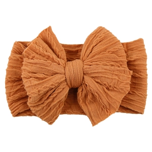 Macro shot of knitted caramel baby headband featuring a large textured bow detail