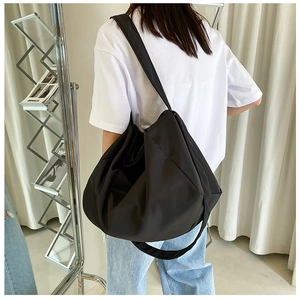 Model view showing the large black oxford cloth bag worn as a shoulder bag in minimalist room
