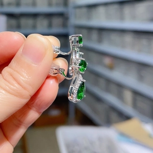 Detail of silver drop earrings featuring green teardrop zircon and white crystal accents