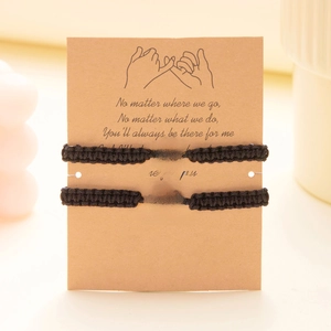 Detail of hand-woven spider and web charm bracelets on a poetic card for couples