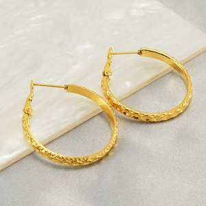 Elegant gold hoop earrings with diamond-cut texture on a shell-textured display