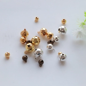 Close-up of gold, silver, and bronze metal bells for DIY crafts on a white background