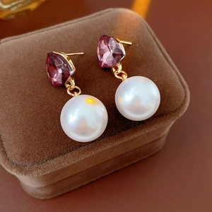 Gros plan sur boucles d'oreilles vintage avec pierre violette et perle sur velours
